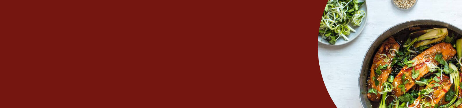 Gekookte zalm met groenten in een pan, met extra groenen en zaden op de achtergrond.