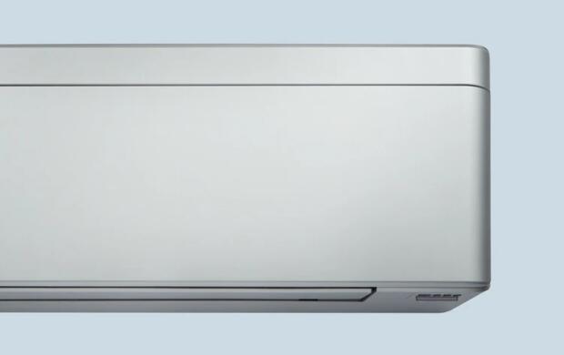 Een close-up van een moderne, minimalistische airconditioner aan de muur.