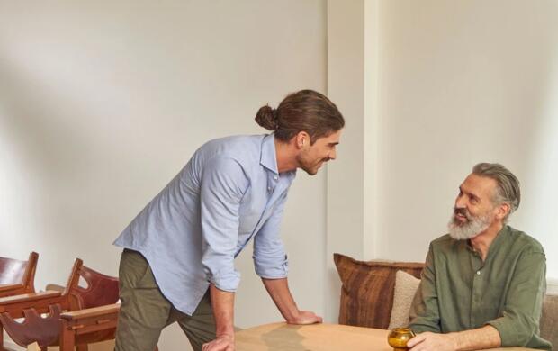 Twee mannen praten aan een tafel in een modern ingerichte kamer.