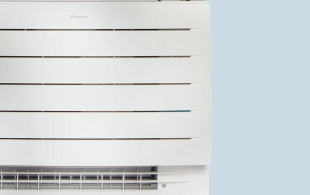 Een witte airconditioner tegen een lichtblauwe achtergrond.