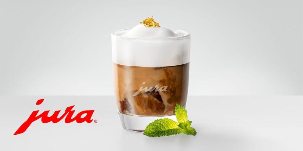 Een glas met koffie en schuim, blaadje munt en een logo met de tekst "jura".