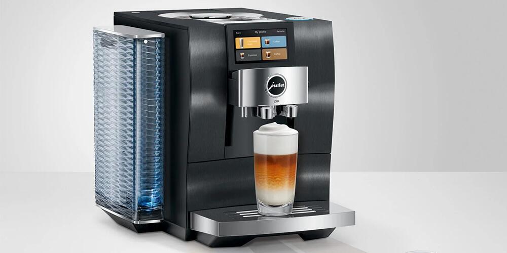 Een moderne koffiemachine met een glazen kopje cappuccino eronder.