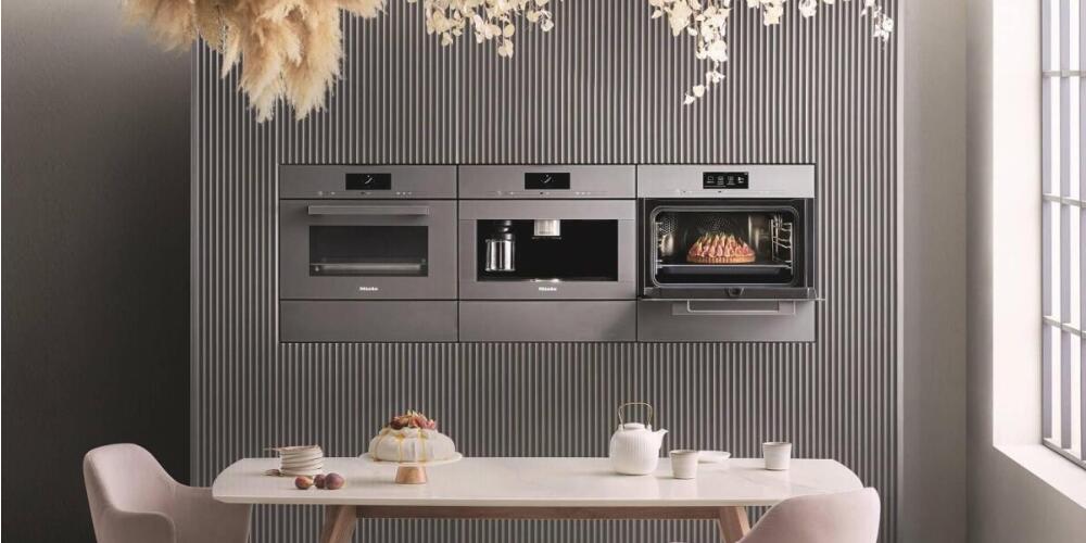 Moderne keuken met ingebouwde ovens en koffiezetapparaat, met gedekte tafel op de voorgrond.