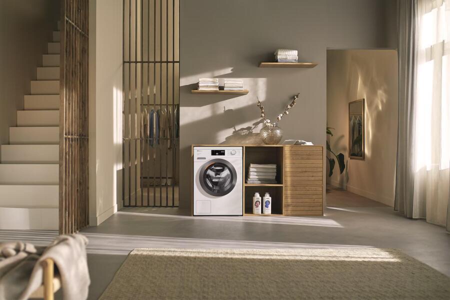 Moderne wasruimte met een wasmachine, houten kast, planken met handdoeken, en subtiele decoraties.