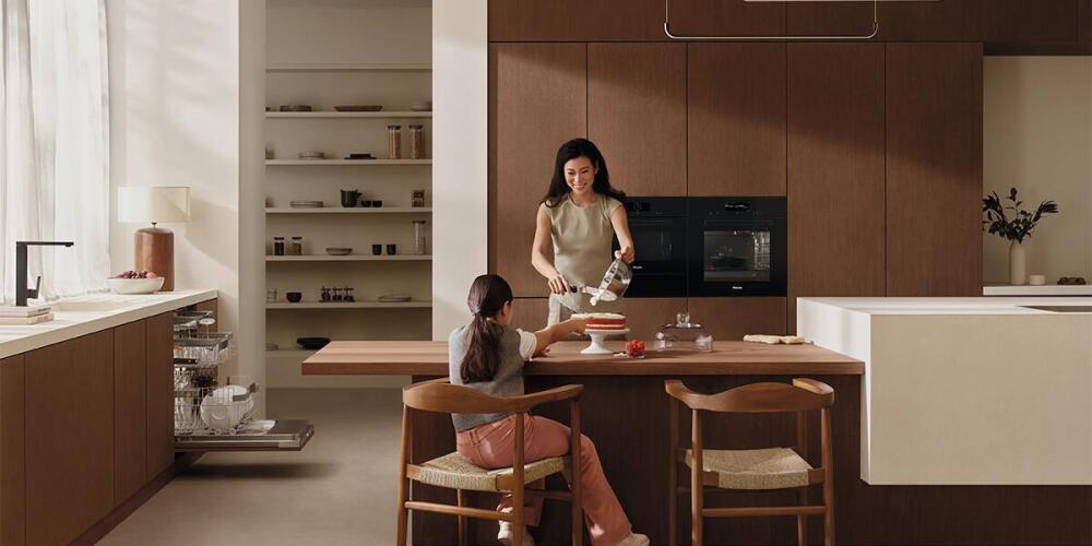 Een volwassen persoon en een kind bereiden samen een maaltijd in een moderne keuken.