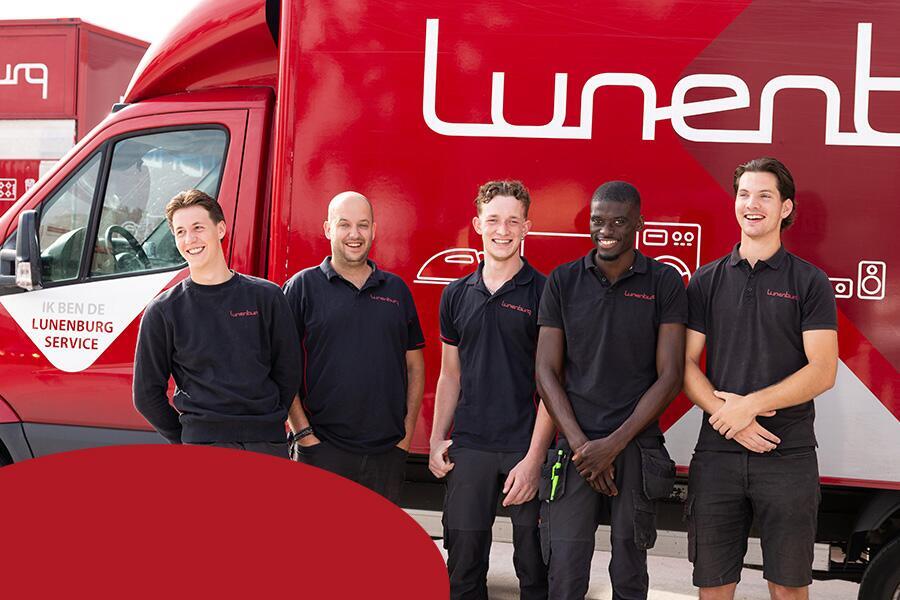 Vijf lachende mannen poseren voor een rode bestelwagen met het logo van Lunenburg.