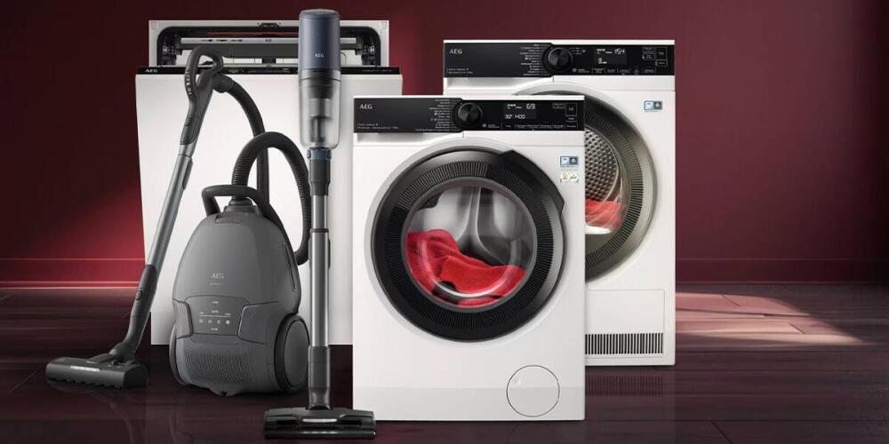 Huishoudelijke apparaten zoals een stofzuiger, wasmachine, droger en vaatwasser op een houten vloer.